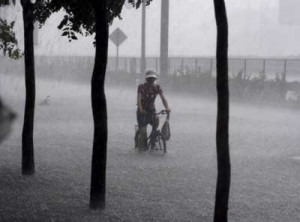 A cyclists tries to ride through heavy rain on a street in Beijing